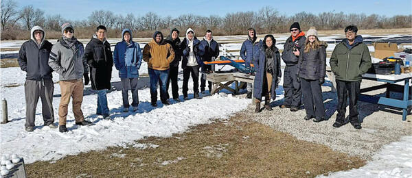 People in winter clothing standing on snowy ground outdoors.