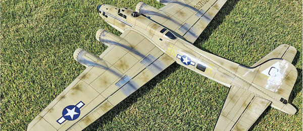 Model airplane of a bomber on grass, painted in military colors, with star insignia.