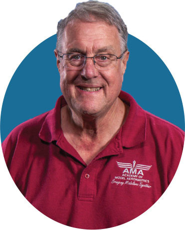 Man in red polo shirt with "AMA" logo, smiling. Blue circular background.