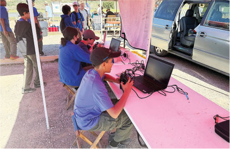 People working at laptops under a tent near an open van.