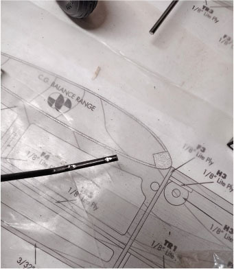 Blueprint with rods and text "C.G. BALANCE RANGE" on paper.