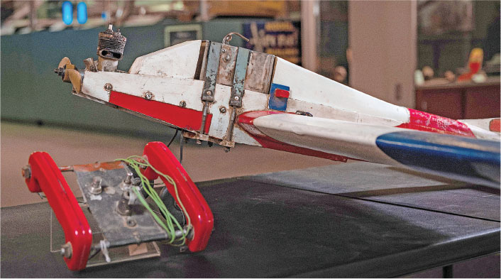Model airplane with colorful stripes on a table, featuring a detached red and metal component.