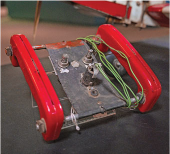 Metal plate with red handles and green wires on a dark surface.