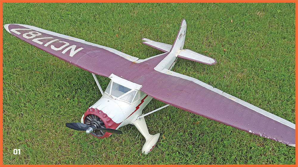 Model airplane with maroon wings on grass, marked NC1787.