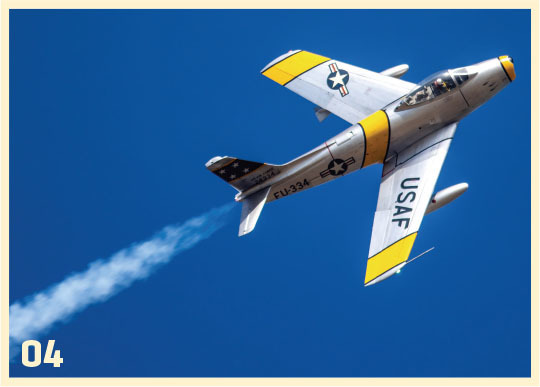 Fighter jet with USAF markings flying, trailing smoke against blue sky.