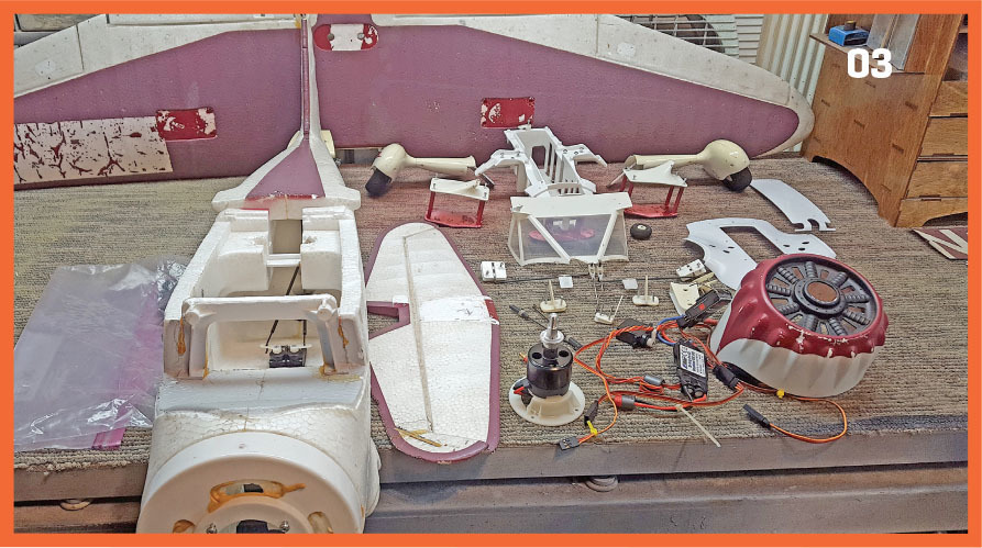 Disassembled model airplane parts on a table, number "03" in corner.