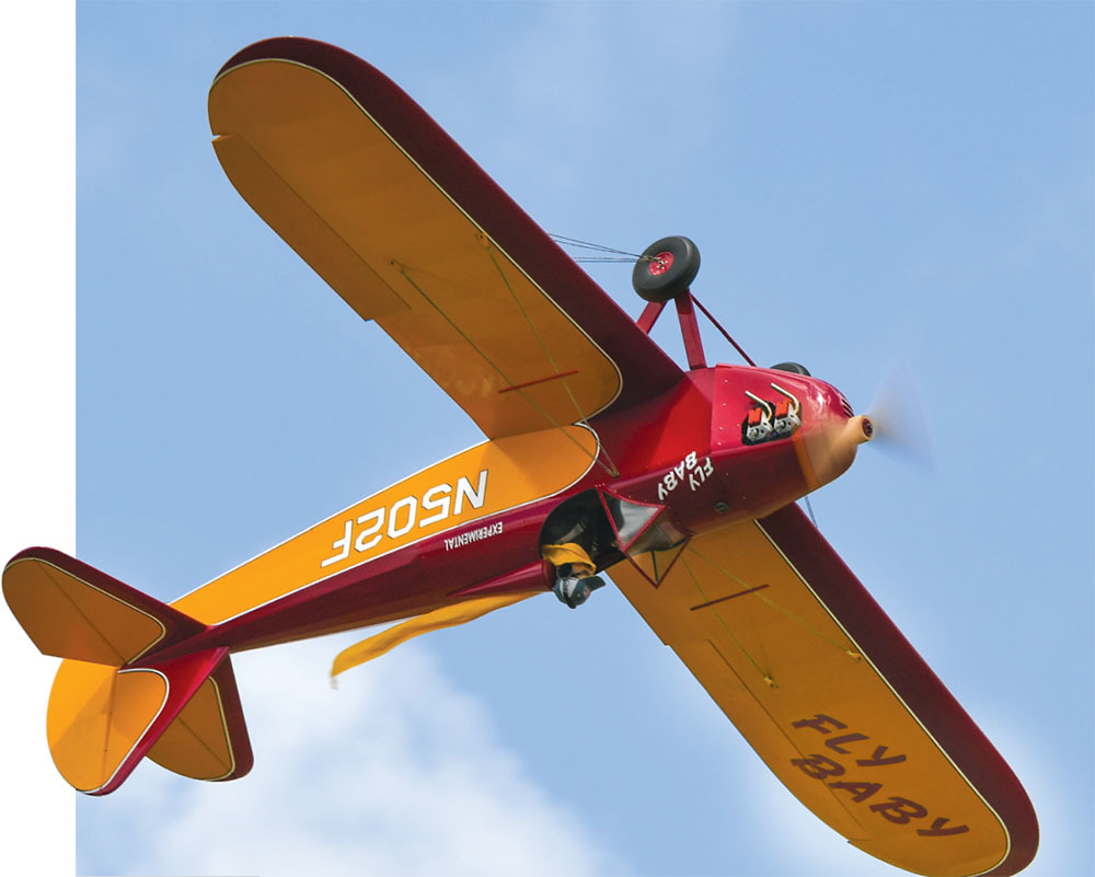 Red and yellow biplane flying against a blue sky, text reads "FLY BABY."