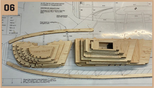 Wooden model ship parts on blueprint with "06" in the corner.
