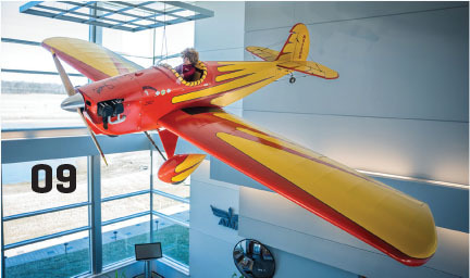 Red and yellow vintage airplane displayed indoors, with "09" on the window.