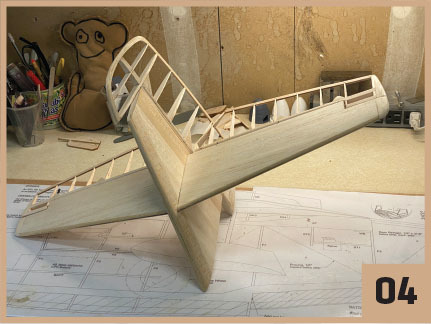 Wooden model airplane framework on a blueprint, number 04 in the corner.