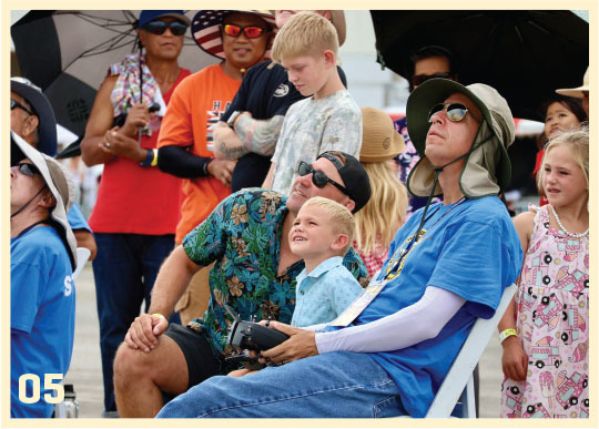 A group enjoys an outdoor show, smiling and looking up.