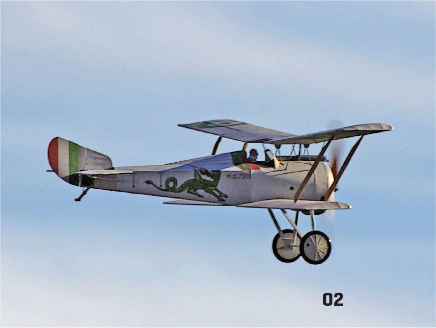 Vintage biplane with dragon emblem, flying in blue sky.