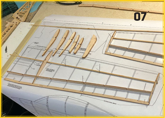 Wooden model aircraft wing assembly on blueprint, number 07 in corner.
