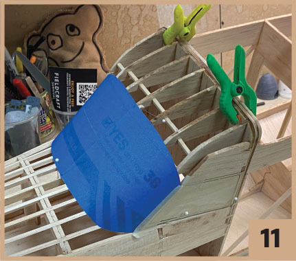 Wooden model framework with blue sheet clamped, numbered 11.