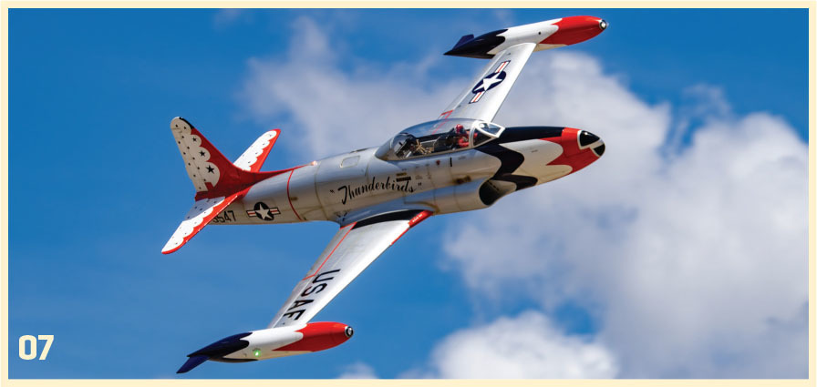 Vintage USAF Thunderbird jet flying in blue sky with clouds.