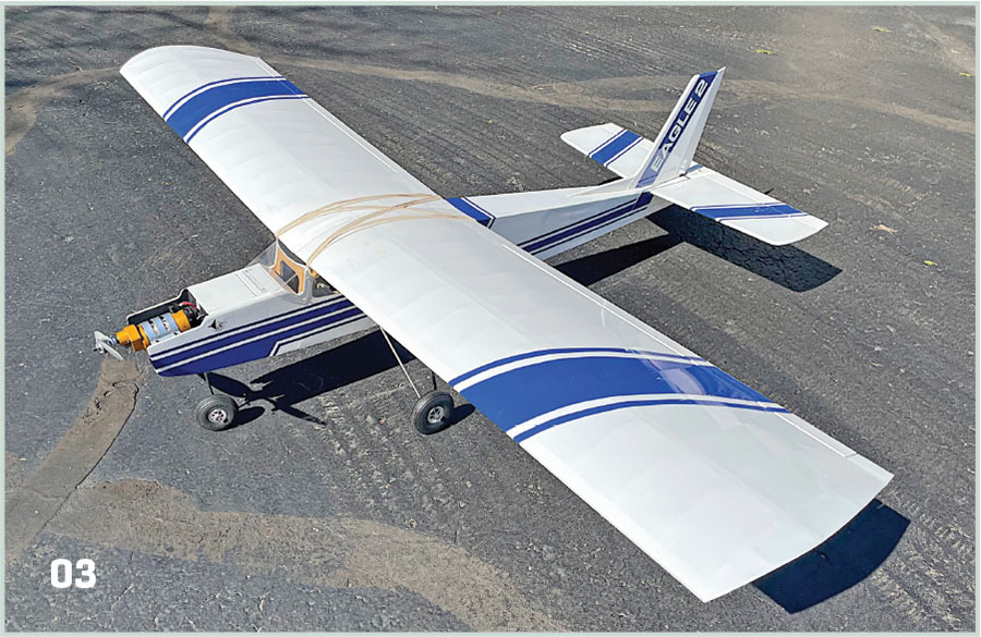 White and blue model airplane labeled "EAGLE 2" on a tarmac.
