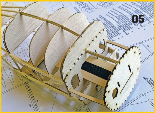 Balsa wood airplane model frame on blueprint, marked "05".