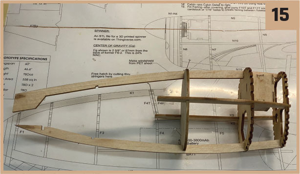 Wooden model airplane frame on a blueprint, marked "15" in the corner.