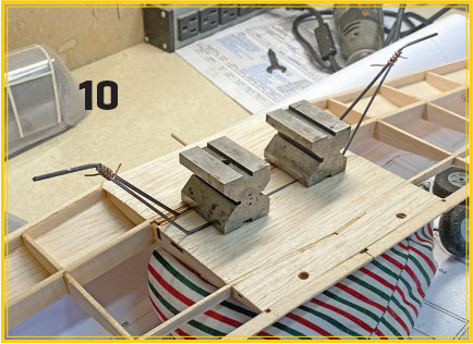 Metal weights on wooden frame with wire and striped cushion. Number 10 in black text.