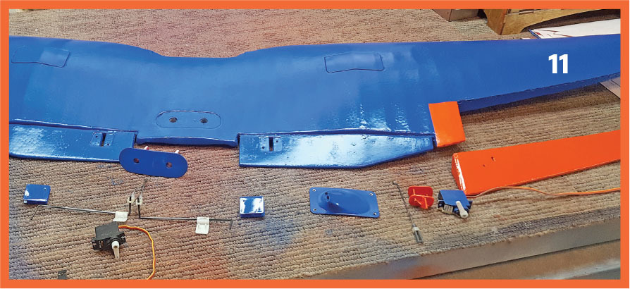 Blue and orange aircraft wing parts on a carpet. Number 11 on the wing.
