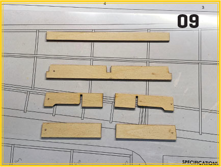 Wooden pieces on a technical drawing sheet labeled "09."