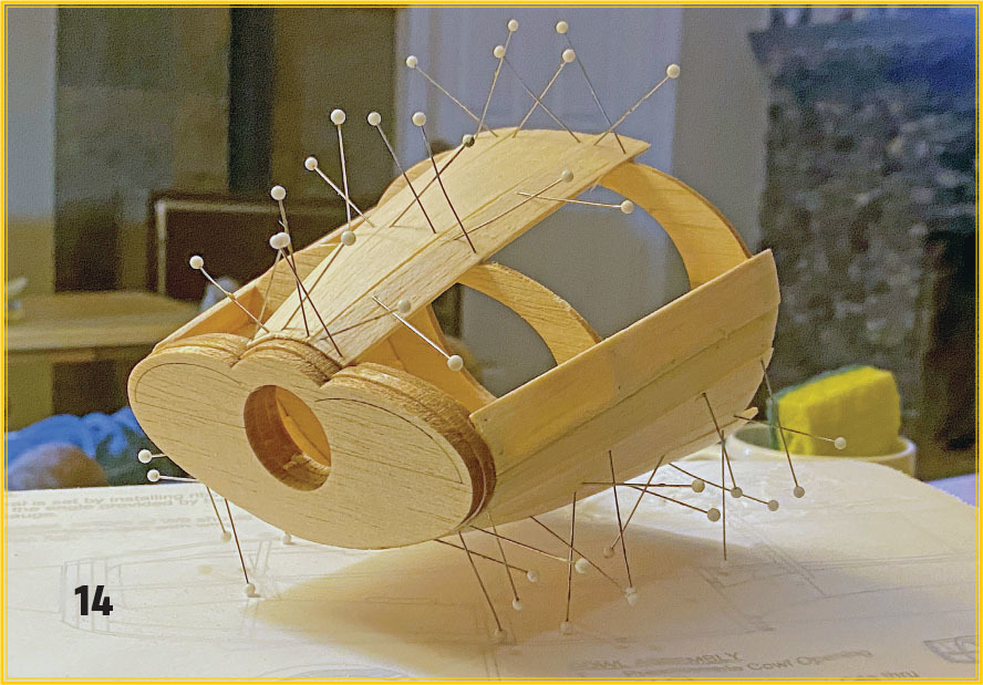 Wooden model with sewing pins on a table. Number 14 in corner.