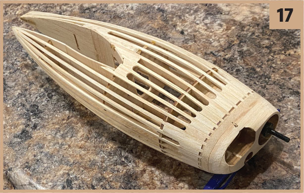 Wooden model airplane fuselage on a marbled surface, number 17 in corner.