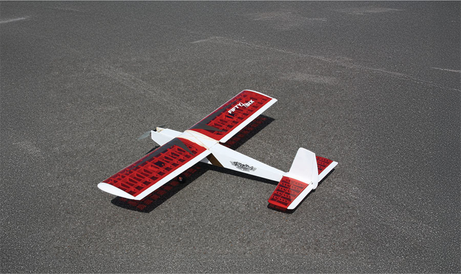 Red and white model airplane on asphalt.