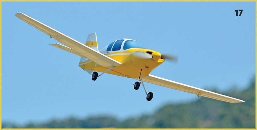 Yellow and white model airplane flying against blue sky, number 17 at top.