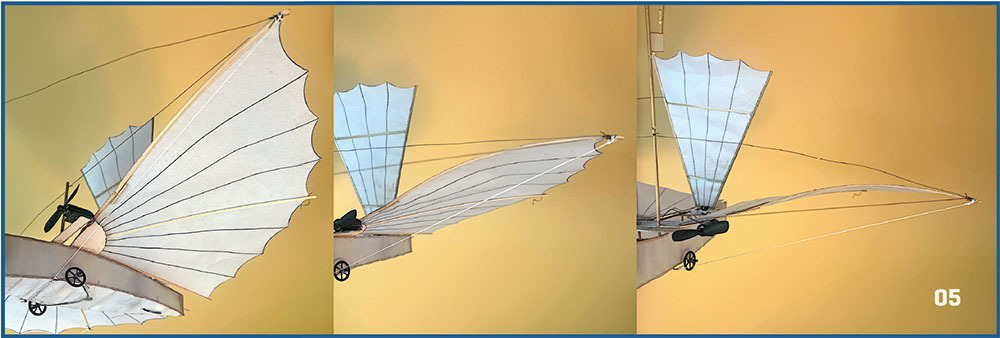 Flying machine models with white fabric wings against a yellow background.