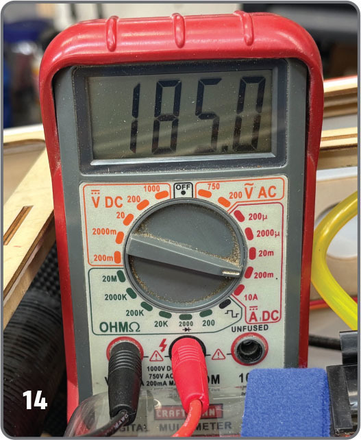 Digital multimeter displaying 185.0 volts with red and black probes connected.