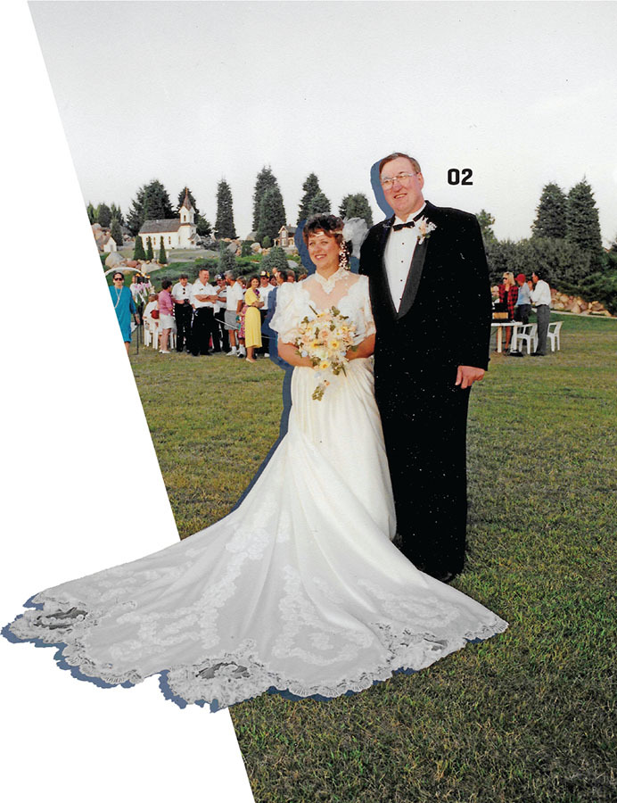 Bride and groom outdoors, bride in long white gown, people and chapel in background.