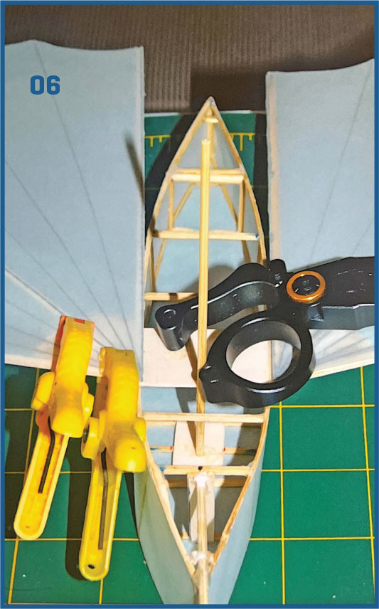 Model boat assembly with clamps on a green mat, number 06 in blue.