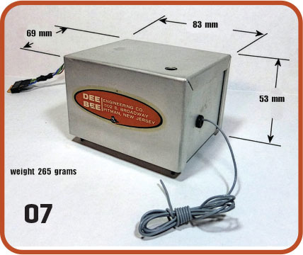 Gray metal box with "DEE BEE" label, measured dimensions, and a coiled cable.