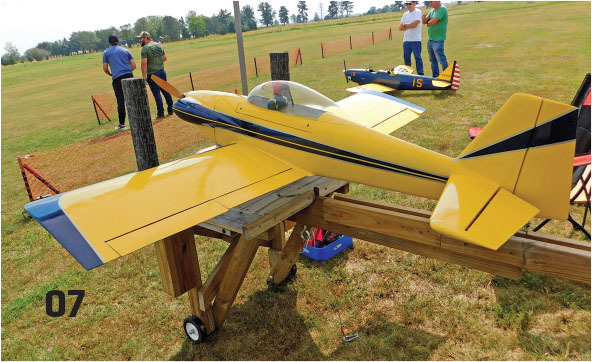 Yellow model airplane on a stand, field in background, number 07.