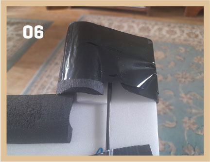 Black foam piece with black tape in living room, number 06 in corner.