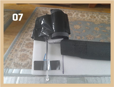 Black tube, silver rod, and tape on table, number 07 in the corner.