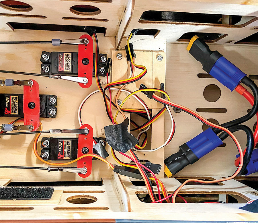 Hitec servos and colorful wires inside a wooden enclosure, with blue and red connectors.