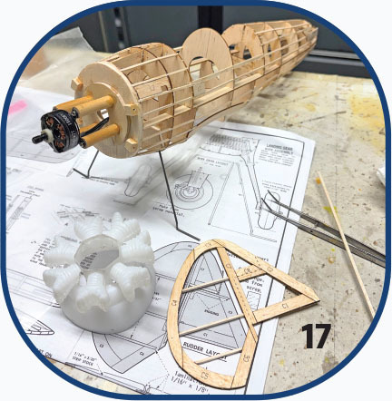 Wooden model airplane frame on engineering plans with parts labeled "17."