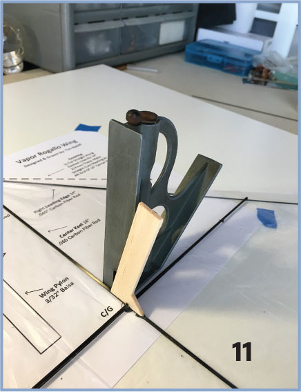 Woodworking square tool on a table with papers and blue tape, number 11 visible.