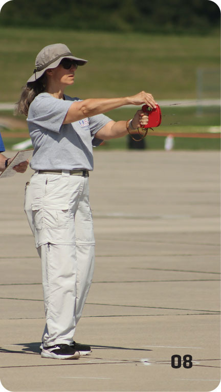 Woman in hat measuring distance on a runway with a tape measure.