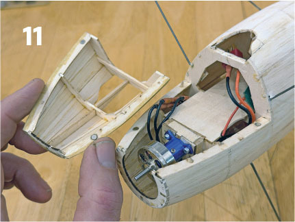 Model airplane assembly showing fuselage opened with visible motor and wiring.