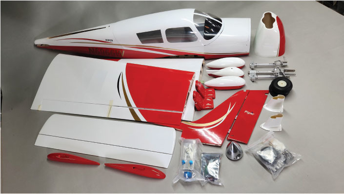Model airplane parts, red and white, neatly arranged on a table.