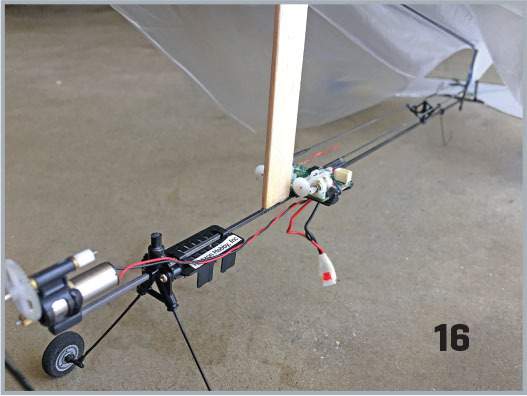 Model glider with detailed machinery and "16" text in a workshop.