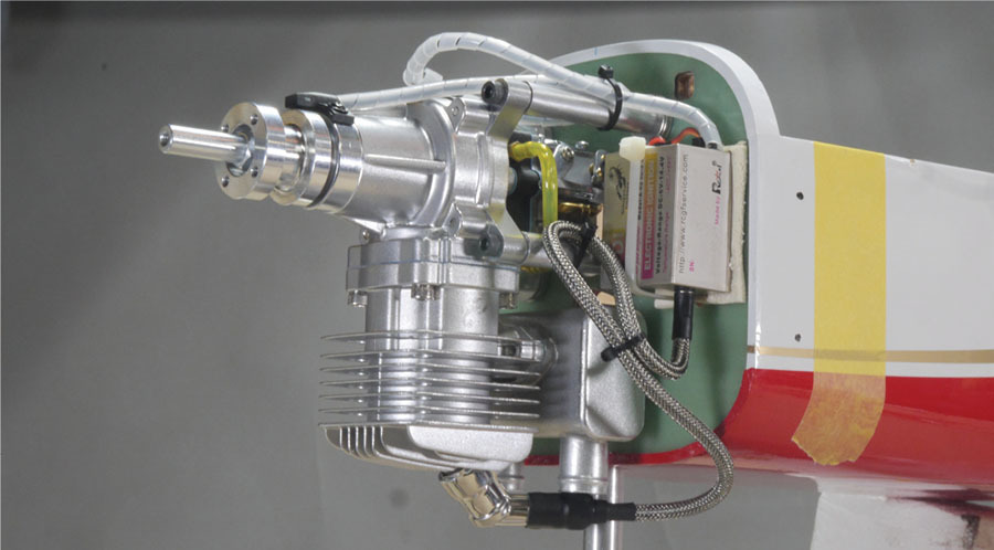 Small engine attached to a white and red wing model aircraft.