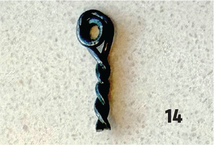 Dark twisted metal object on a speckled surface with number 14.