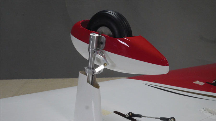 Red and white model airplane wheel assembly on a gray background.