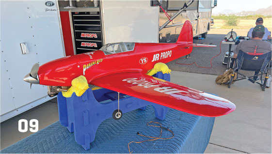 Red model airplane on a blue stand, marked "JR PROPO."