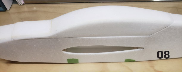 White foam model car with number 08 on wooden surface.