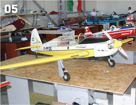 Model airplanes displayed on tables in a warehouse, one labeled "F-PFZE."